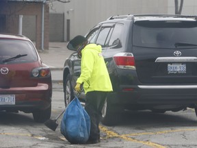 A worker scoops up latex gloves, tossed away by shoppers before getting into their vehicles, in the parking lot at a Metro grocery store at Eglinton Ave. E. and Markham Rd. in Scarborough on Wednesday, March 25, 2020.