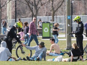 Montreal police officers check the identification of people in a city park Saturday, May 2, 2020, as the COVID-19 pandemic continues in Canada and around the world.