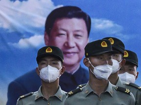 Soldiers of the People's Liberation Army's Honour Guard Battalion wear protective masks as they stand at attention in front of photo of China's president Xi Jinping at their barracks outside the Forbidden City, near Tiananmen Square, on May 20, 2020 in Beijing, China.