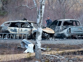 An RCMP investigator inspects vehicles destroyed by fire at the residence of Alanna Jenkins and Sean McLeod, both corrections officers, in Wentworth Centre, N.S. on Monday, April 20, 2020.