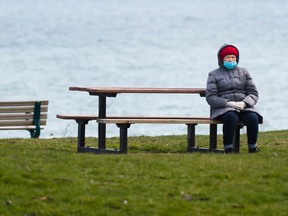 A woman sits alone with Lake Ontario in the background in Toronto on Monday, April 27, 2020.