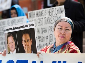 Turnisa Matsedik-Qira, of the Vancouver Uyghur Association, demonstrates against China's treatment of Uyghurs while holding a photo of detained Canadians Michael Spavor, left, and Michael Kovrig outside a court appearance for Huawei Chief Financial Officer Meng Wanzhou at the British Columbia Supreme Court in Vancouver on May 8, 2019.