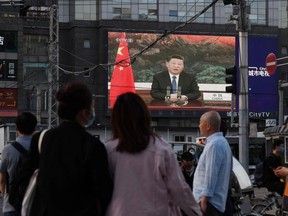 A news program shows Chinese President Xi Jinping speaking via video link to the World Health Assembly, on a giant screen beside a street in Beijing on May 18, 2020.