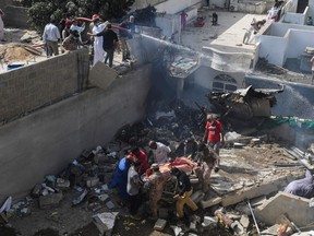Rescue workers move a body from the site after a Pakistan International Airlines aircraft after crashed at a residential area in Karachi on May 22, 2020.