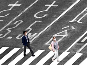 People wearing face masks amid concerns of COVID-19 cross a street in Tokyo on May 25, 2020. Japan's prime minister lifted the state of emergency in the Tokyo region that day, after last week lifting it for the region around Osaka and Kyoto.