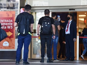 People wait in line to have their body temperature checked before entering a shopping mall in Brasilia on May 27, 2020, on the first day of business reopening in the city amid the COVID-19 coronavirus pandemic.