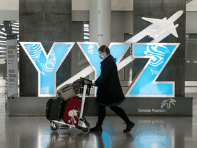 A person wearing a mask walks through Toronto Pearson Airport's Terminal 1 on May 20, 2020.
