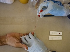 A health worker conducts a COVID-19 rapid antibody test on a resident inside a columbarium on May 20, 2020 in Quezon city, Metro Manila, Philippines.