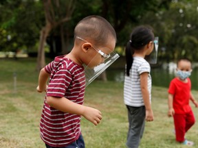 Children wearing protective shields spend the afternoon at Rama IX Park after the Thai government eased isolation measures, amid the coronavirus disease (COVID-19) outbreak, in Bangkok, Thailand, May 17, 2020.