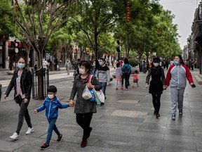 People wearing face masks as a preventive measure against the COVID-19 coronavirus walk on a street in Beijing on May 4, 2020.