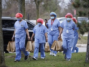 Healthcare workers wearing protective gear carry meals provided by Maple Leaf Sports & Entertainment (MLSE) outside Centenary Hospital in Toronto,  April 24, 2020.