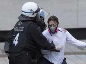 Montreal police push back a protester during a demonstration calling for justice in the death of George Floyd and victims of police brutality on Sunday, May 31, 2020.