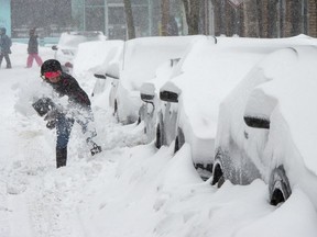A woman shovels out her car during a snowstorm, Friday, February 7, 2020 in Montreal. It may not feel like it the morning after a blizzard, but Canada gets less snow than it used to.