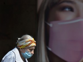 An elderly woman wearing a face mask walks past an advertising placard in Kiev, Ukraine, on May 4, 2020.