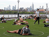 People relax in designated circles marked on the grass at Brooklyn’s Domino Park on May 18, 2020, in New York. The circles were added after the park became severely overcrowded during a patch of unseasonably warm weather about a week earlier.