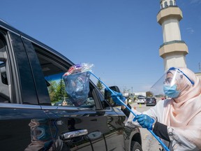 An Islamic Society of North America Mosque community member hands out candy to children in a drive through Eid celebration on Sunday, May 24, 2020. The celebration lasted hours with thousands participating.