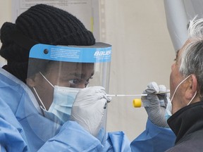 A health-care worker prepares to swab a man at a walk-in COVID-19 test clinic in Montreal North, Sunday, May 10, 2020, as the COVID-19 pandemic continues in Canada and around the world.