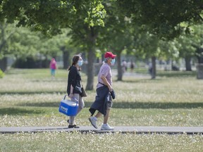 People wear face masks as they walk through a park in Montreal, Saturday, May 30, 2020, as the COVID-19 pandemic continues in Canada and around the world.
