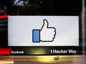 The entrance sign to Facebook headquarters is seen through two moving buses in Menlo Park, California, October 10, 2018.