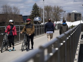 People cross the Adawe Crossing footbridge in Ottawa, in the midst of the COVID-19 pandemic, on Sunday, May 10, 2020.