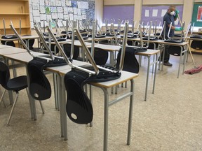A cleaner helps clean a classroom at Eric Hamber Secondary school in Vancouver, B.C. Monday, March 23, 2020.