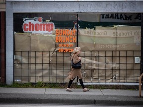 A woman walks past a restaurant closed due to COVID-19, in Vancouver, on Wednesday, May 6, 2020. British Columbia's workplace safety agency has released new guidelines as businesses across the province get set to reopen.