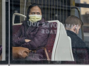 A woman wears a mask as she rides a TTC streetcar in Toronto on Friday, March 20, 2020. The gradual reopening of Canada's economy will not mean business as usual for the country's public transit agencies.