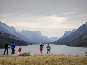 Tourists look out over Waterton Lake in Waterton National Park, Alta., Friday, Aug. 9, 2019.