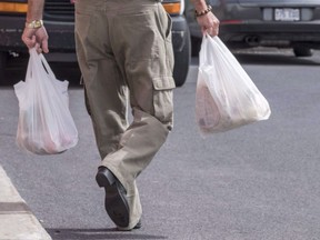 A shopper leaves a grocery store carrying his groceries in plastic bags Tuesday, August 30, 2016 in Brossard, Que. In mid January the British Columbia government announced it was looking at a province-wide ban on single-use plastic grocery bags to put an end to a piece-meal, city-by-city approach to the problem of plastic pollution.