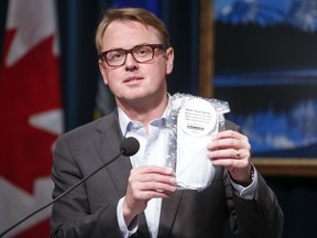 Alberta Minister of Health Tyler Shandro holds a package of four non-medical masks that will be available to Albertans to prevent the spread of COVID-19, in Calgary, Alta., Friday, May 29, 2020.