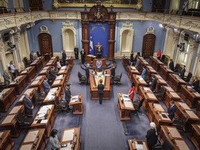 Members of the National Assembly stand in a minute of silence to honor the victims as the legislature resumes with limited attendance of members during the COVID-19 pandemic, Wednesday, May 13, 2020 at the legislature in Quebec City.