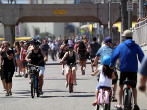 People ride and walk on a path along beach amid the coronavirus pandemic on May 15, 2020 in Huntington Beach, California.  Beaches across the state have started to reopen with rules in place such as maintaining social distancing and restrictions against lying or sitting down on the beach in order to slow the spread of COVID-19.