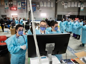 Medical staff work at a computer terminal as they prepare for the opening of the COVID-19 Assessment Centre at Brewer Park Arena in Ottawa, during a media tour on Friday, March 13, 2020.