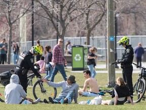 Montreal police officers check the identification of people in a city park Saturday, May 2, 2020, as the COVID-19 pandemic continues in Canada and around the world.
