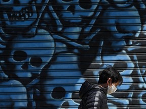 A man wearing a mask to protect against COVID-19 walks past a mural in the Brooklyn borough of New York City on May 12, 2020.