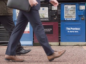 A man walks past newspaper boxes in downtown Vancouver in 2016.