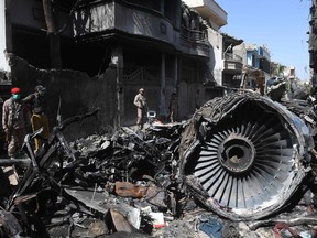 Security personnel stand beside the wreckage of a plane at the site after a Pakistan International Airlines aircraft crashed in a residential area days before, in Karachi on May 24, 2020.
