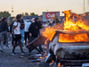 Protesters throw objects onto a burning car outside a Target store near the Third Police Precinct on May 28, 2020 in Minneapolis, Minnesota, during a demonstration over the death of George Floyd.