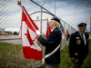 A Royal Canadian Legion member prepares a flag to salute before a repatriation ceremony at CFB Trenton for the six Canadian Forces personnel killed in a helicopter crash off the coast of Greece, May 6, 2020.