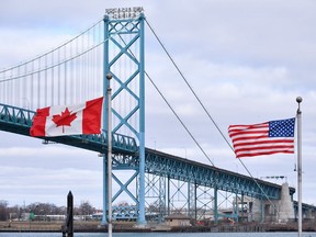 Canadian and American flags fly near the Ambassador Bridge at the Canada-USA border crossing in Windsor, Ont. on Saturday, March 21, 2020. Unique challenges are facing residents in Canadian and U.S. border cities and towns amid a ban on non-essential travel between the two countries during the pandemic.