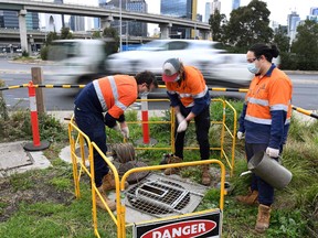 This photo taken on May 19, 2020 shows hydrographer Steven Paull (L) and trainee hydrographers Andrew Lamb (C) and Kingsley Moss (R) taking a sample from a sewer in Melbourne.