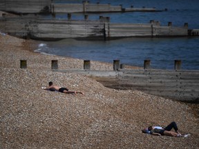 Sun-seekers observe social distancing on the beach in Eastbourne, southern England on May 9, 2020, as life in Britain continues over the May bank holiday weekend, during the nationwide lockdown due to the novel coronavirus COVID-19 pandemic.