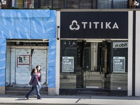 Pedestrians wearing masks walk past a store for lease on Toronto’s Queen Street during the COVID-19 pandemic on May 13, 2020.