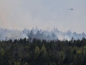 A Department of Natural Resources helicopter, drops water on a wildfire, near Porters Lake, N.S. on Saturday, May 23, 2020. Residents in the area were asked to evacuate as firefighters dealt with the fire, which at one point jumped highway 107 which remains closed.