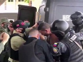 Venezuelan soldiers wearing face masks surround a suspect moved from a helicopter after what Venezuelan authorities described was a "mercenary incursion", at an unknown location in this still frame obtained from Venezuelan government TV video, May 4, 2020.