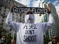 A man holds a skateboard bearing George Floyd's name above his head as thousands of people gather for a peaceful demonstration in support of Floyd and Regis Korchinski-Paquet and protest against racism, injustice and police brutality, in Vancouver, on May 31.