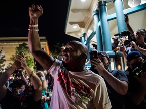 Mawuli Davis (C), a member of Beacon Hill Black Alliance for Human Rights, raises his hand and celebrates as crew members remove the the 30-foot Confederate monument which is been brought down on June 19, 2020, in Decatur northeast of Atlanta, Georgia. Hundreds of people cheered as crews worked to move the Confederate monument from the Decatur Square on the eve Juneteenth.