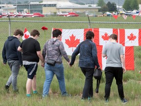 The Canadian Forces Snowbirds jets are seen in the background as a family pays their respects in Kamloops, B.C., Monday, May 18, 2020.