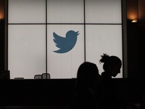 In this file photograph taken on August 14, 2019, employees walk past an illuminated Twitter logo as they leave the company's headquarters in San Francisco.