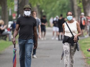 People wear face masks as they walk through a city park in Montreal, Saturday, June 27, 2020, as the COVID-19 pandemic continues in Canada and around the world.